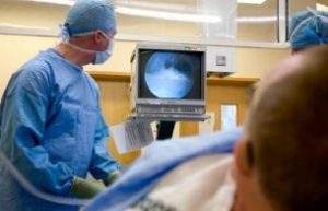 врач смотрит на экран проводя эндоскопический метод удаления пяточной шпоры