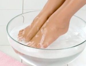 девушка парит ноги в ванночке с горячей водой